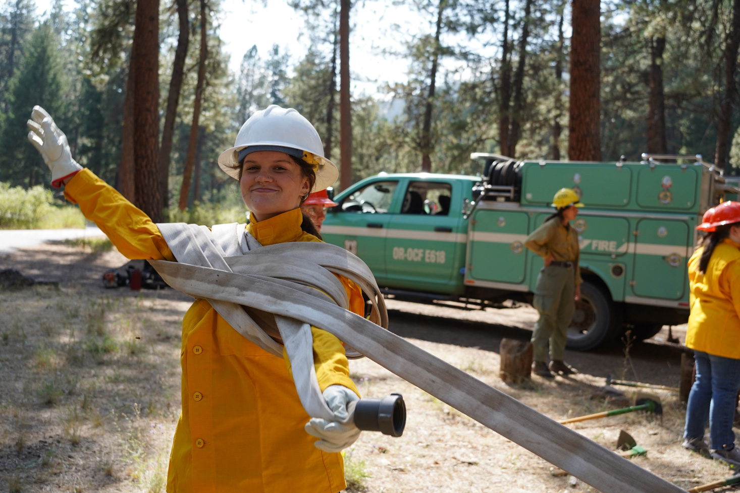 woman in the forest coiling a firehose
